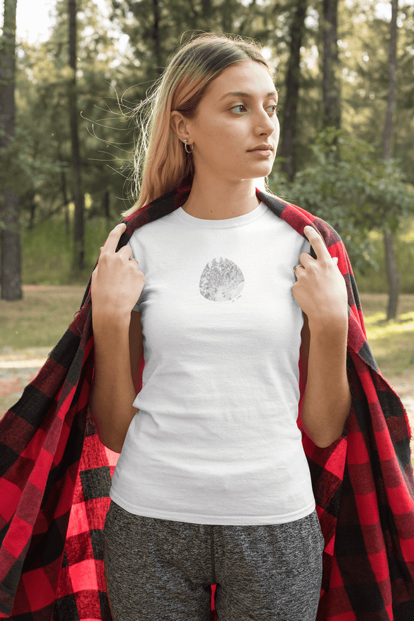 woman wearing white tshirt with vintage photo print of snowy pine trees and the text ok, pine