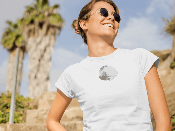 woman wearing white tshirt with vintage photo print of palm trees and seaside with the text palm trees & vitamin sea