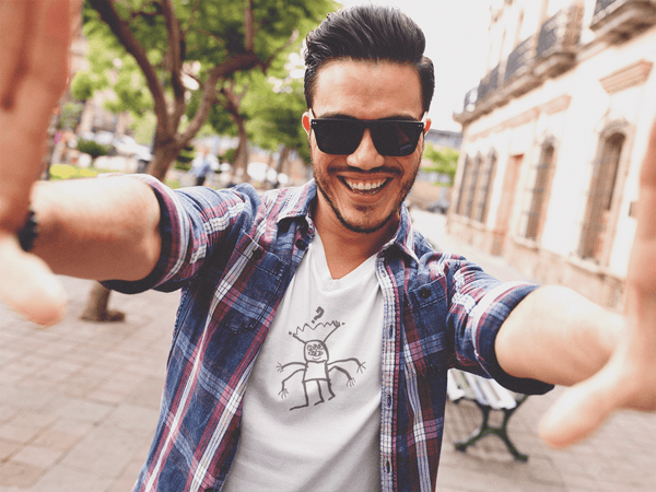 man taking a selfie wearing white unisex tshirt with handrawn graphic of artistic alien