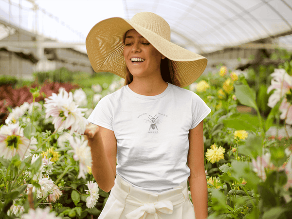 woman in floppy straw hat wearing white womens tshirt with vintage graphic logo of bee trademark 