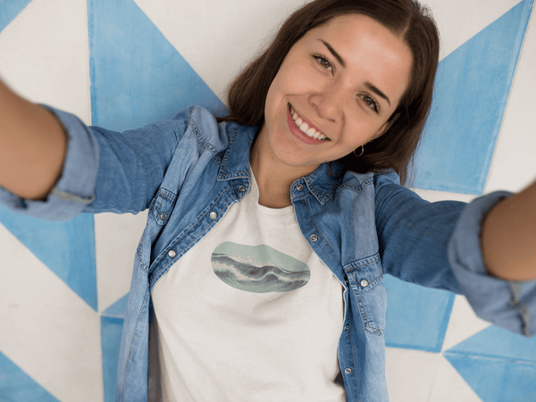 woman wearing white unisex tshirt with vintage graphic woodblock print of ocean waves in light aquamarine color